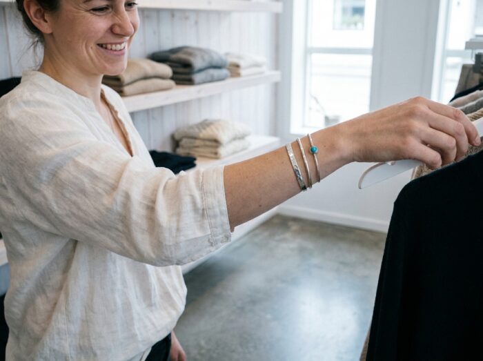 Femme portant des bracelets fins argentés dans une boutique minimaliste tendance 2026