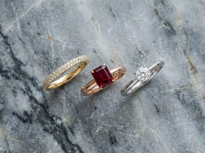Gros plan de trois bagues de luxe en or posées sur du marbre, mettant en valeur l'artisanat et les pierres précieuses
